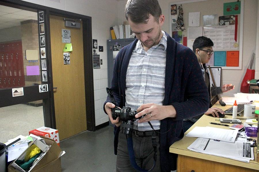 Mr. Smith checks the settings on a SLR camera during 2nd period Photography.
