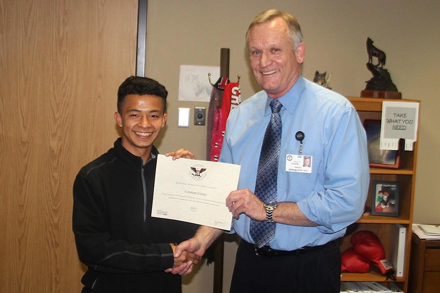 Cristian Garay, 10, receives the Presidents Volunteer Service award from Principal Hughes Wednesday , March 2.