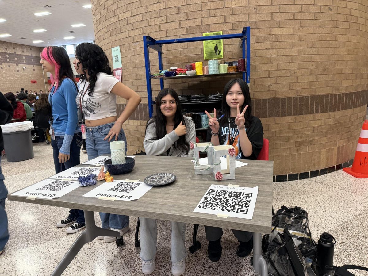 Valeria Villavicencio (10) and Jenny Dinh (12) speak to students about Ceramics Club and show the pieces available to purchase.